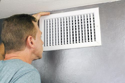 Man inspecting return vent